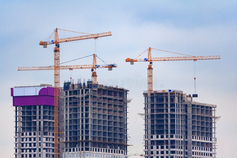Three orange tower cranes build a panel houses stock photo