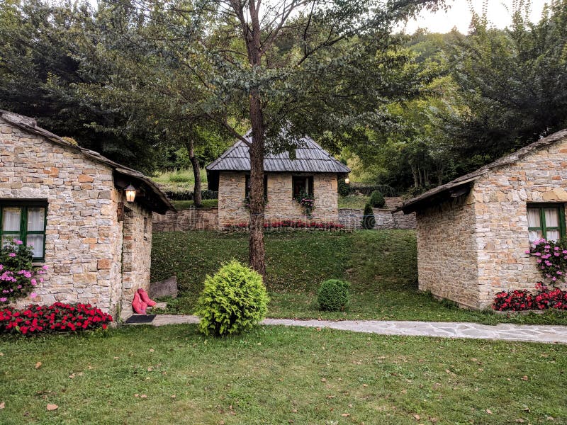 Three stone rustic cozy mountain village houses with colorful flowers and brick stone facade surrounded by green grass and nature royalty free stock image