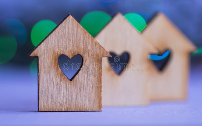 Three wooden houses with hole in form of heart on colorful bokeh background royalty free stock photos